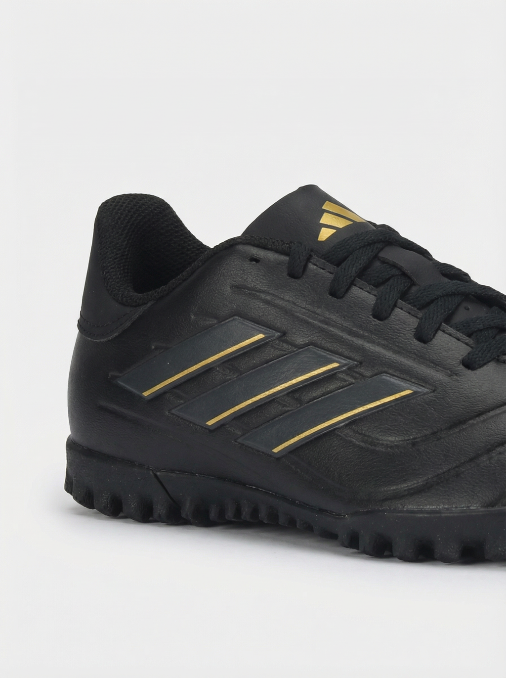 Black soccer shoe with gold stripes on a white background