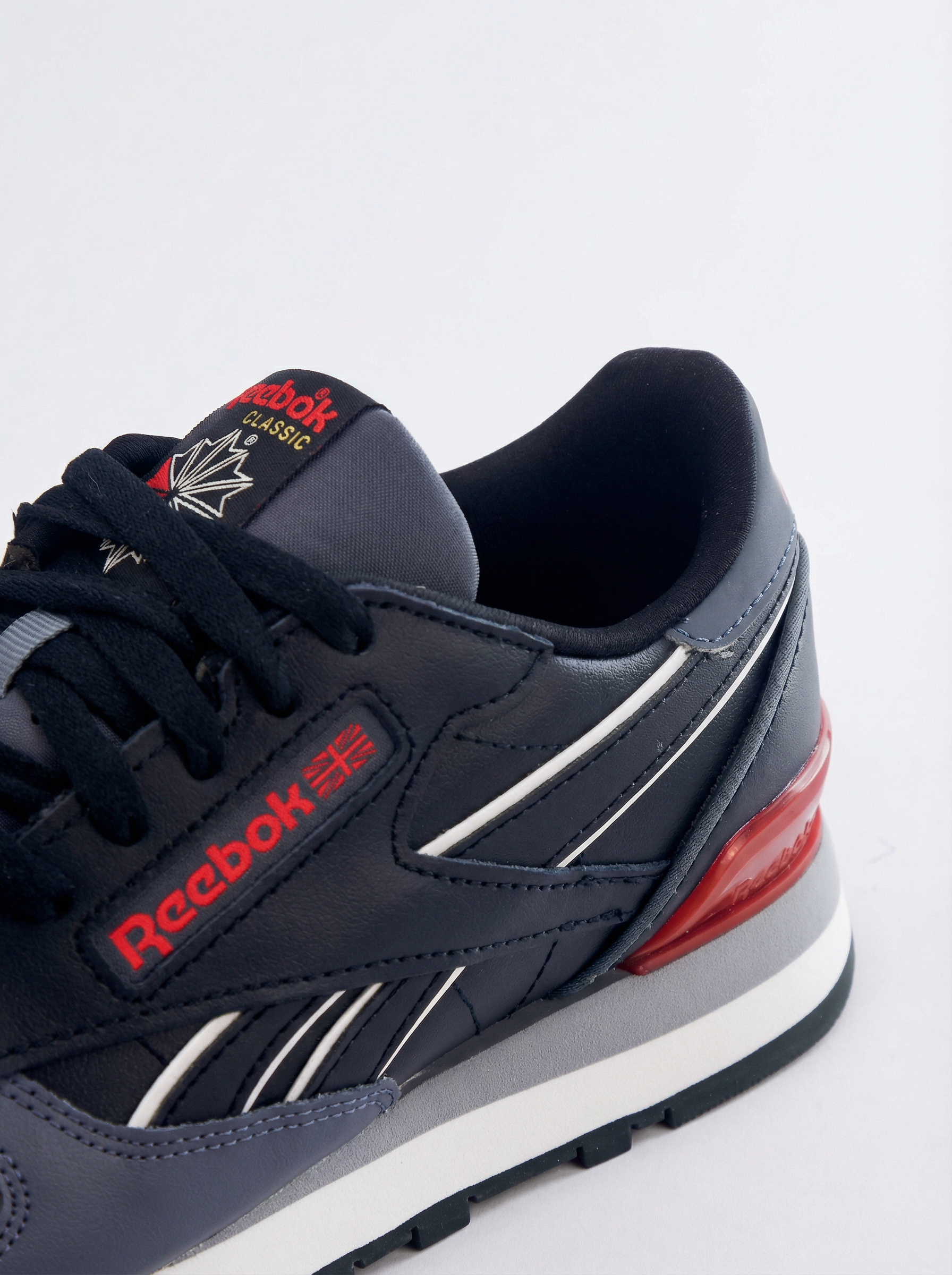 Navy Reebok sneaker with red accents on a white background