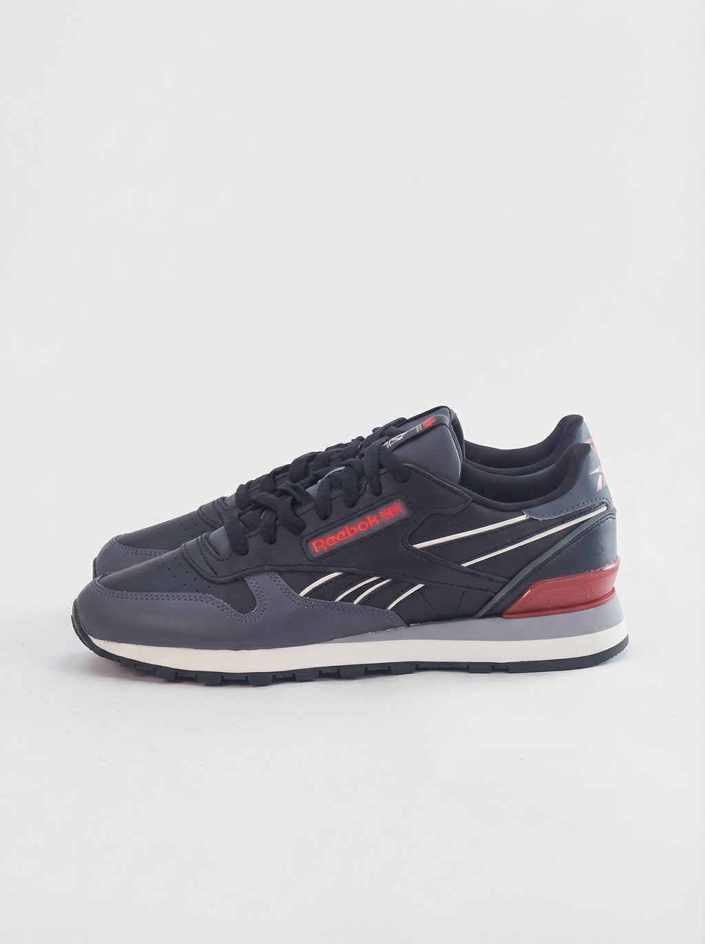 Navy blue sneaker with red accents on a light gray background