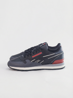 Navy blue sneaker with red accents on a light gray background